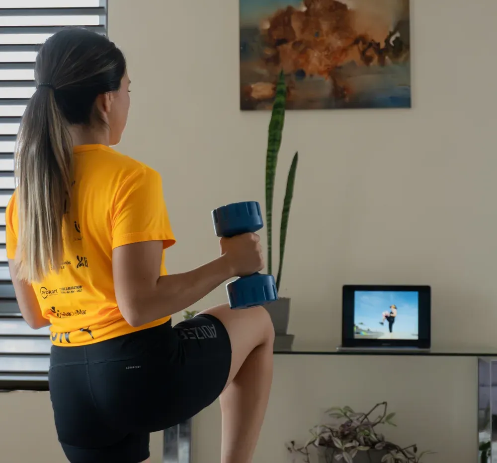 Mujer entrenando en casa siguiendo el programa en su laptop